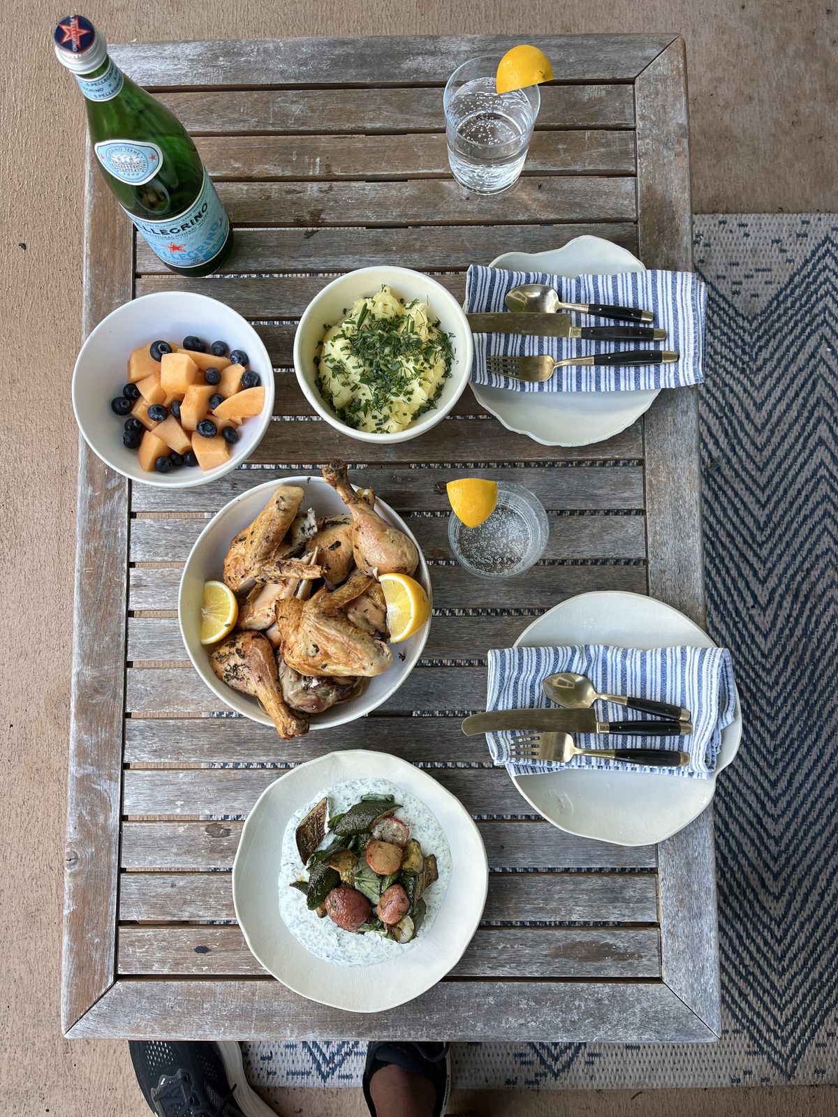 Family-style outdoor spread with roasted chicken, rice, and fresh fruit